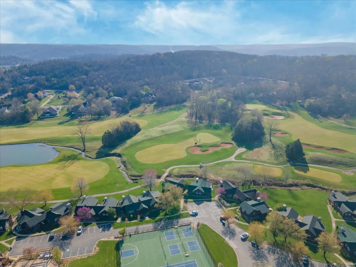 This wide-angle outdoor view captures the community’s golf course, a picturesque pond, adjacent townhouses, and visible tennis courts. The setting is lively yet serene, with open green spaces inviting outdoor activities and group gatherings.