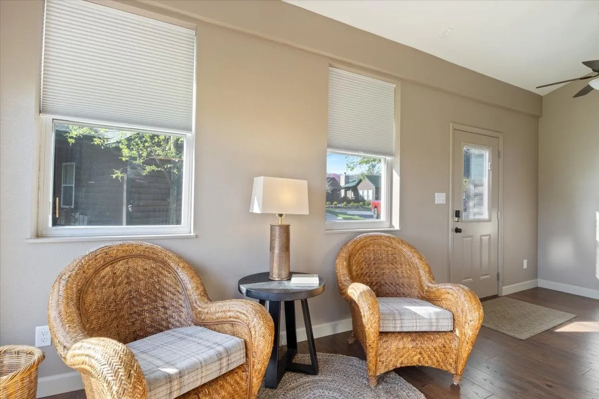 A cozy nook with wicker chairs, a table lamp, and a side table by the entrance door, warmed by morning light. The scene feels welcoming and encourages casual conversation or a tranquil moment with coffee before the day’s adventures begin.